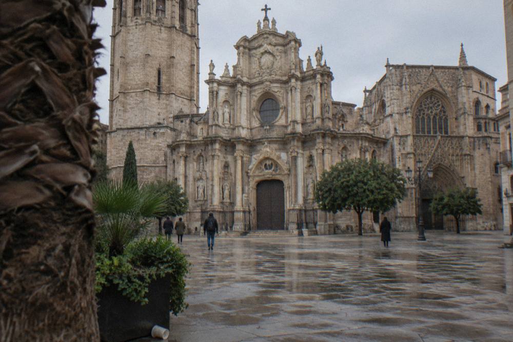Baroque main facade of Valencia Cathedral seen from a quiet square with palm trees