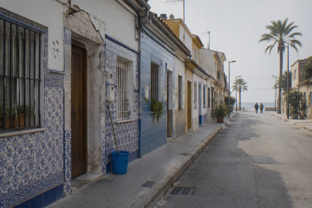 Row of low houses decorated with colourful ceramic tiles along a quiet coastal street