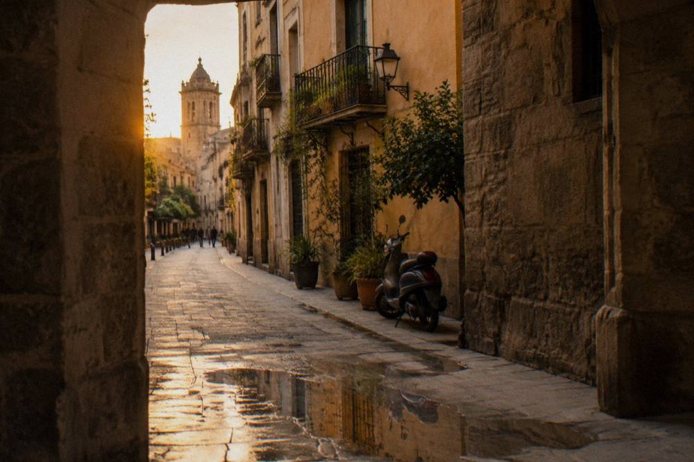 A narrow medieval street in Valencia with tall stone buildings and warm evening light on the facades.