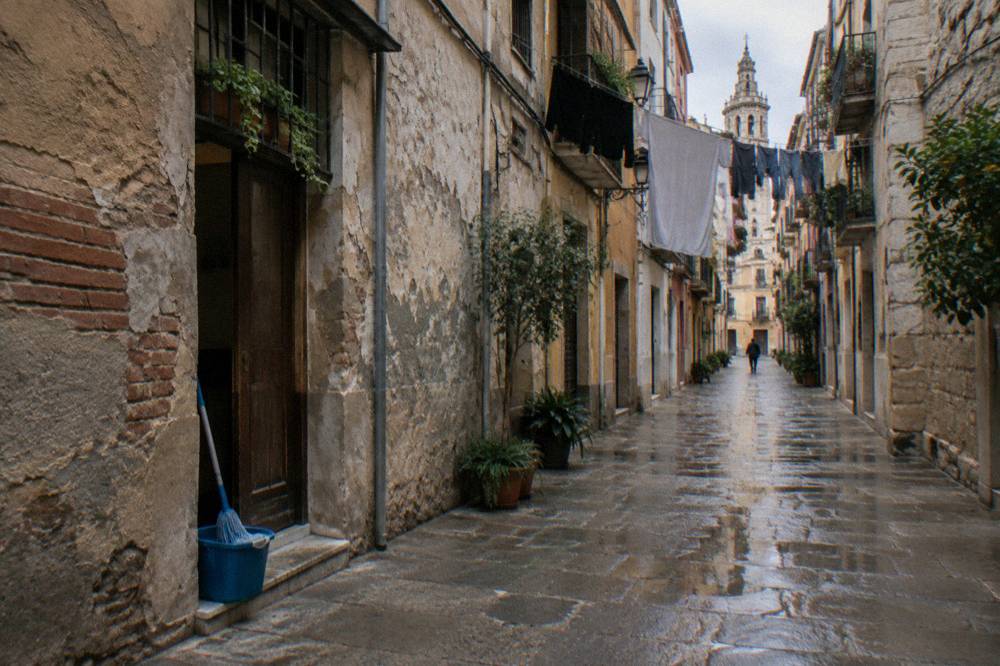 Narrow old town street in Valencia with worn stone walls and hanging laundry above