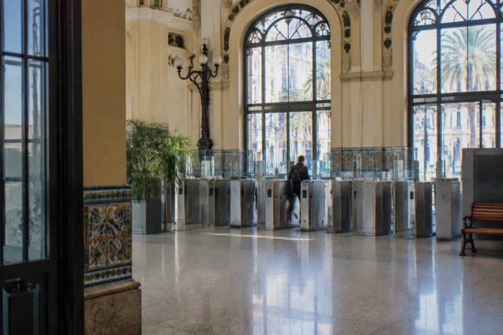 Valencia metro concourse with a row of steel gates and a pale tiled floor
