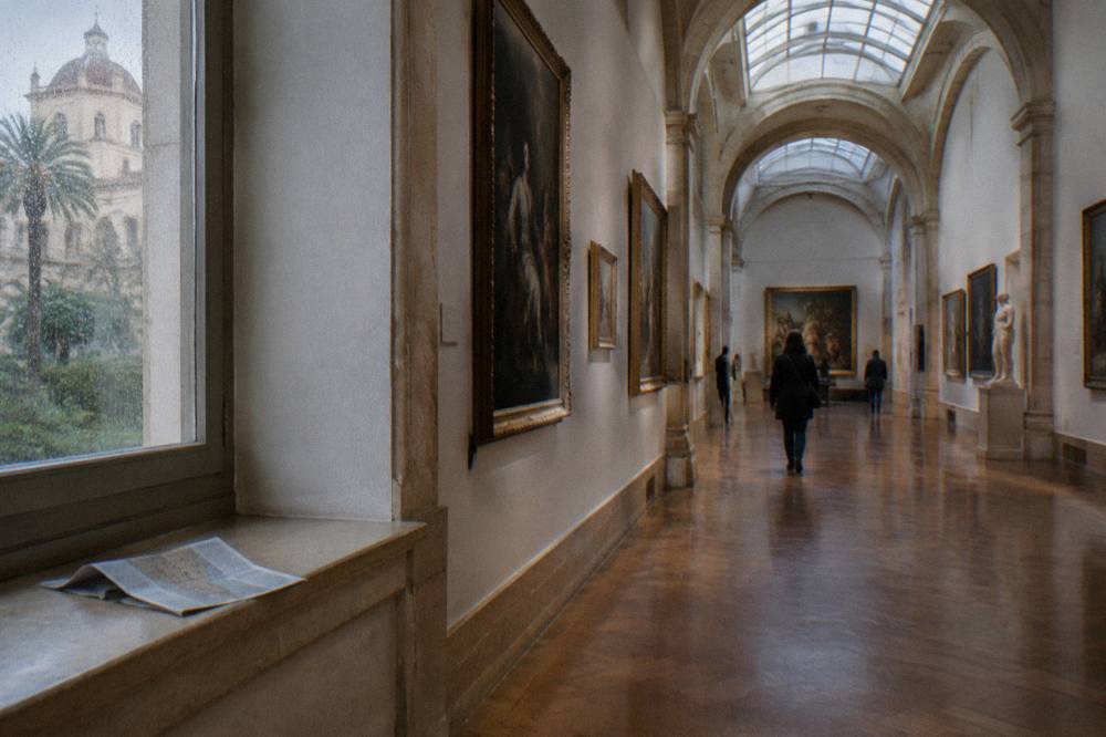 Gallery hall with paintings on light walls and stone arches