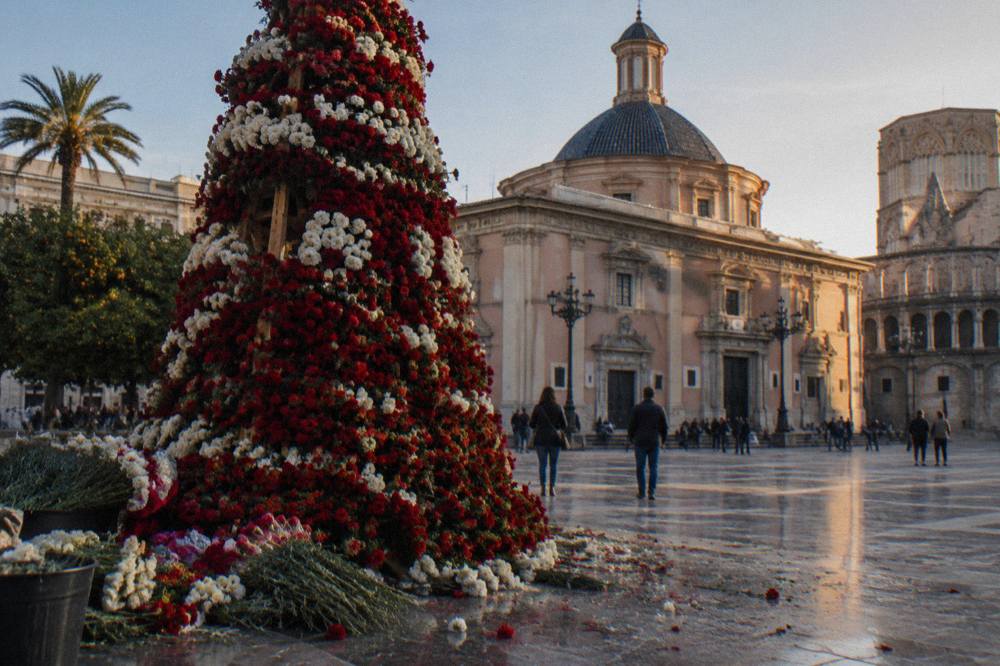 Flower bouquets stacked into a tall floral mantle on a framework beside a church facade