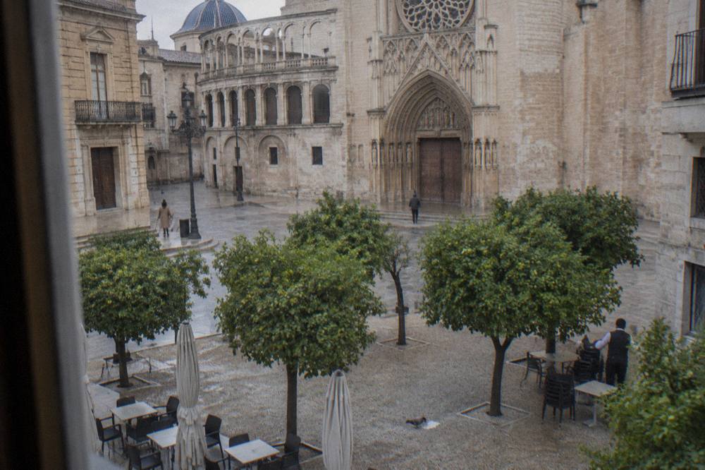 Sunlit plaza in Valencia's old town with orange trees and historic stone facades