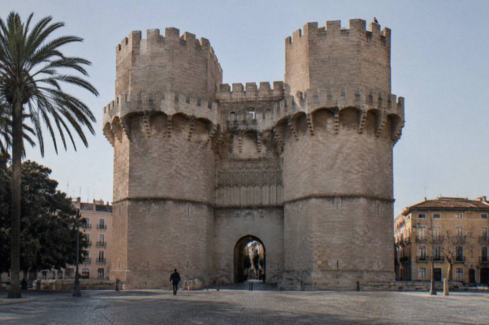 Gothic stone gate tower rising over a plaza in the old town of Valencia
