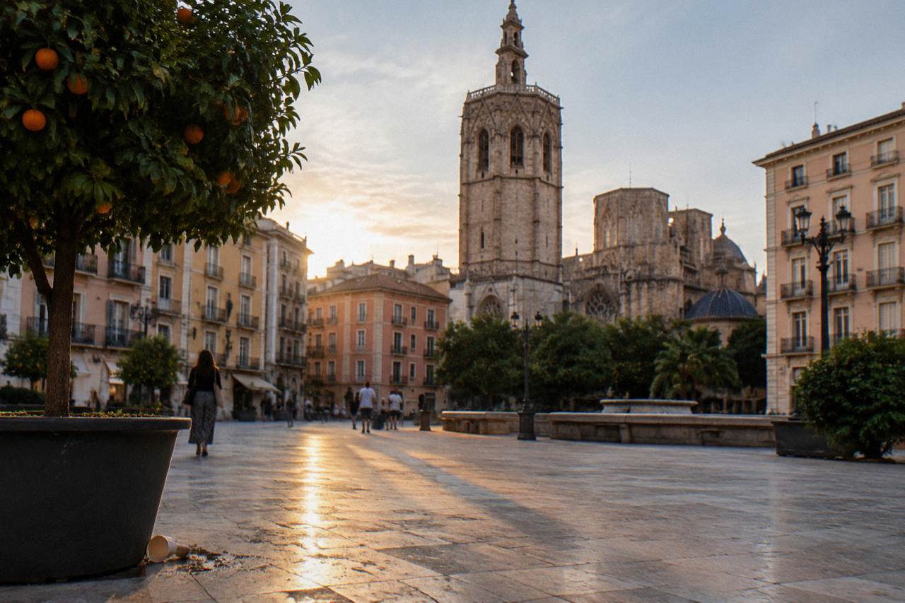 Sunlit plaza with historic stone buildings and a bell tower in Valencia