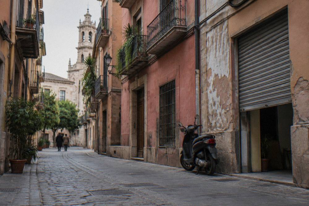 A narrow medieval street in Valencia's old town with pastel facades and balconies