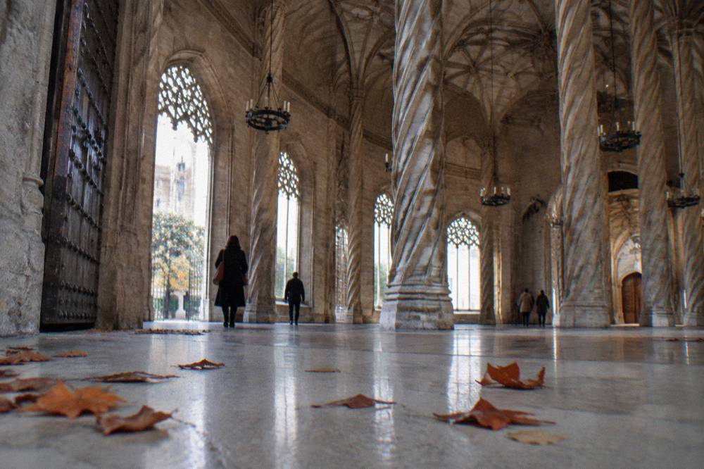 A grand Gothic hall with slender twisted stone columns reaching to a vaulted ceiling