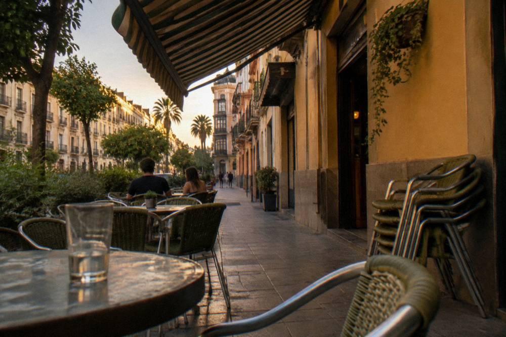 Cafe tables and chairs on a Ruzafa pavement with striped awnings and painted walls above
