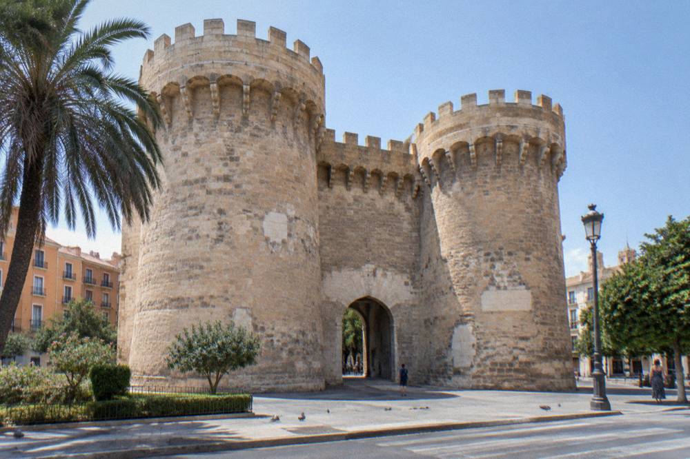 The arched gateway of the Quart towers with warm stone walls and a clear sky