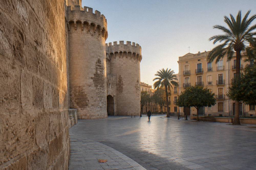A quiet square beside a stone gate tower with plain facades and empty pavement