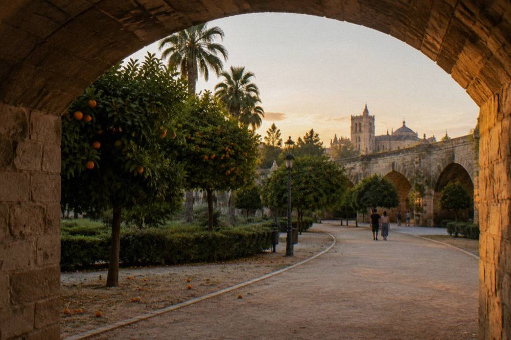 Wide garden path curving through the old riverbed with orange trees and a stone bridge spanning the park