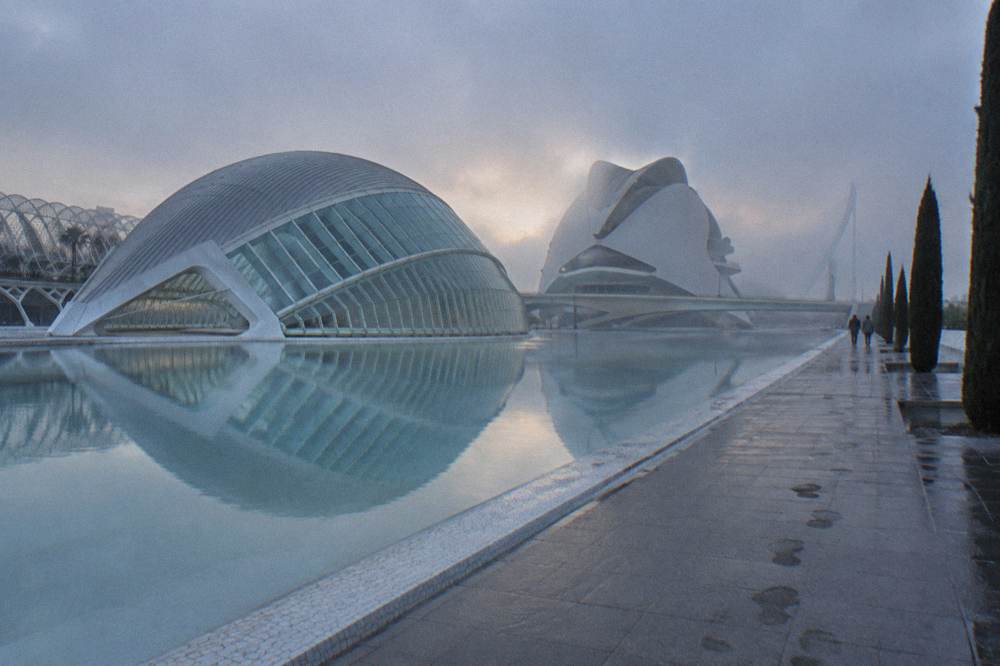 White curved buildings and still reflecting pools of the cultural complex seen from the free walkways