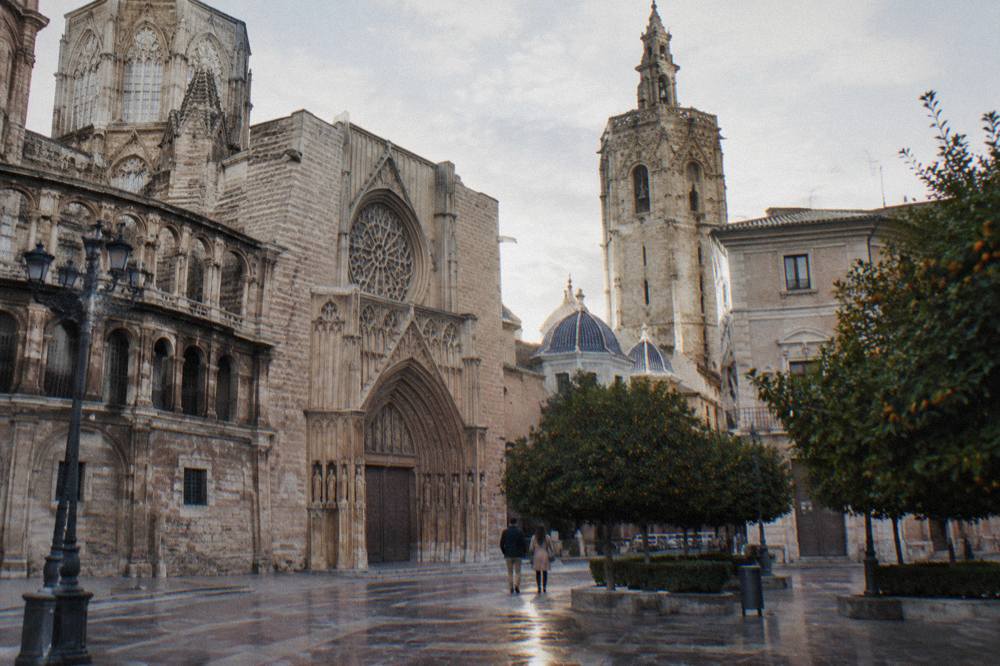 Broad pale stone cathedral front and bell tower above orange trees on a sunlit square