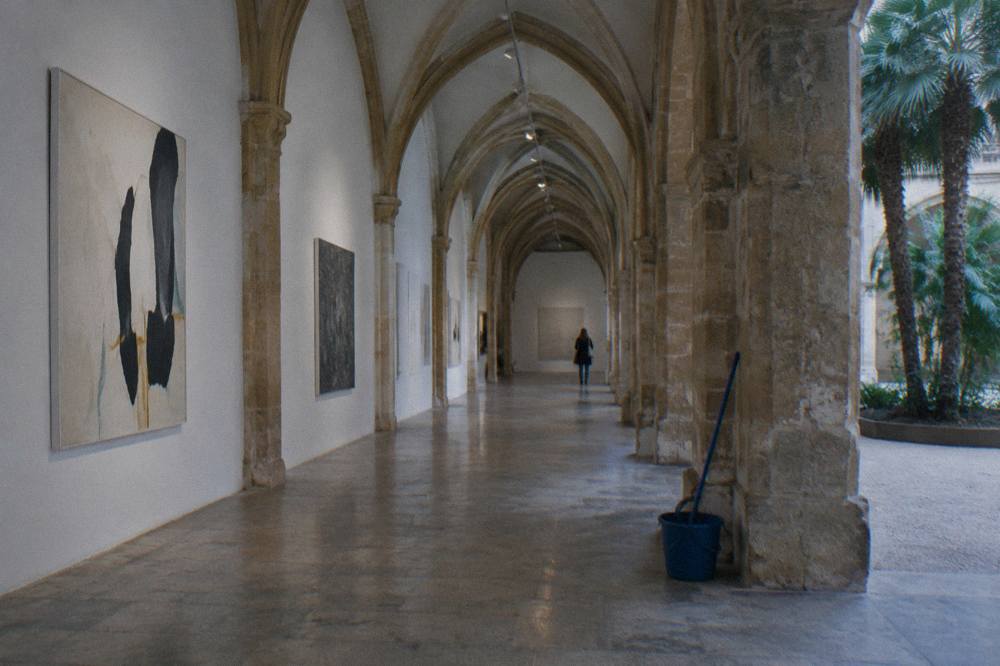 Museum gallery hall with stone arches and paintings on the walls