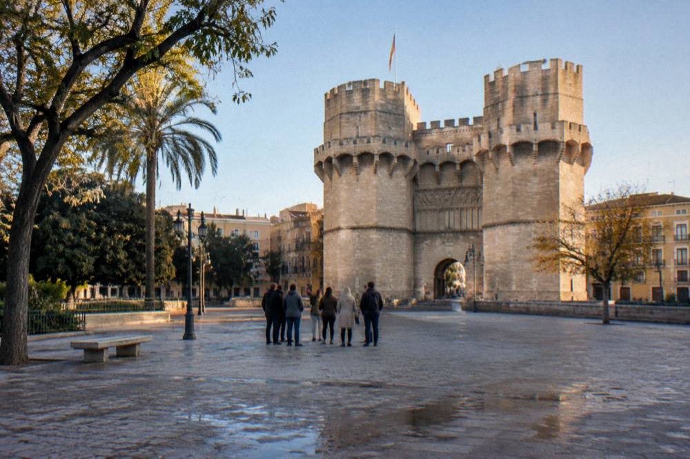 Group of visitors standing around a guide in a historic square with a bell tower behind