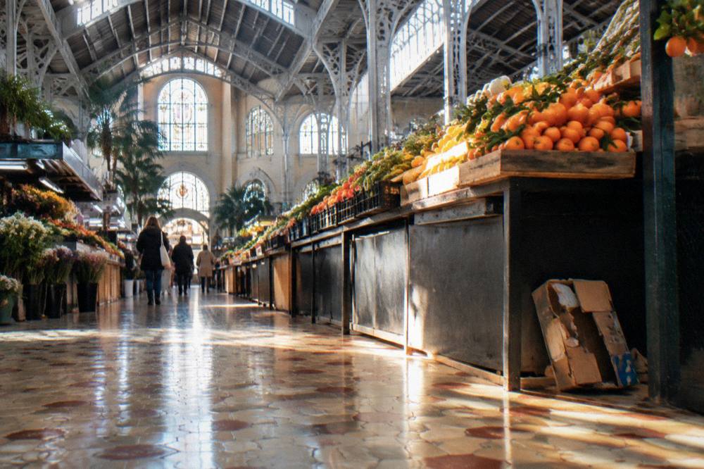 Market hall interior with produce stalls under an iron and glass roof