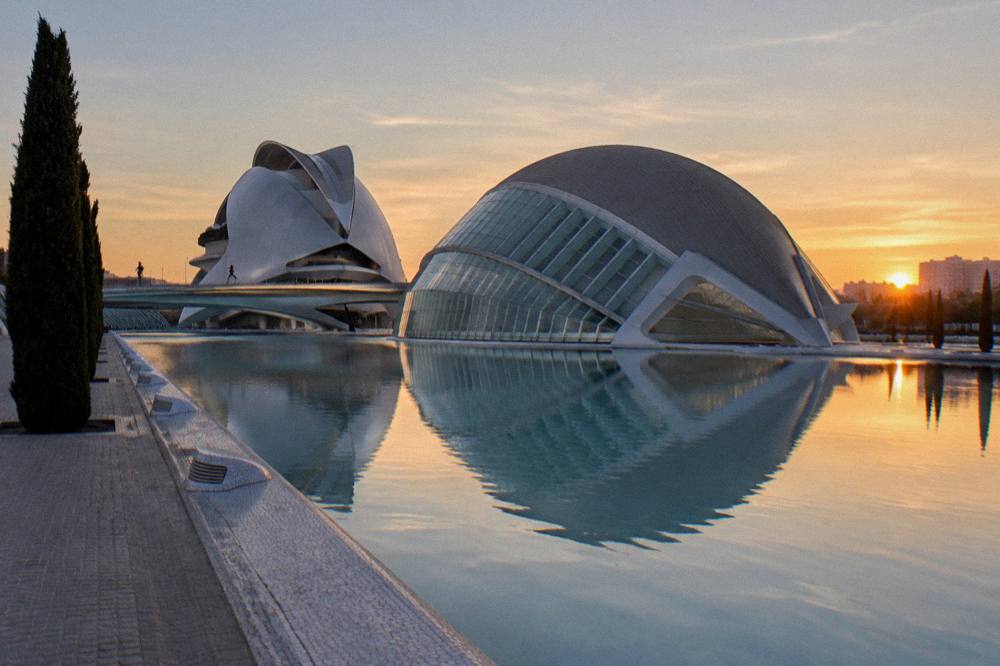 Modern white complex of curved buildings reflected in a long still pool