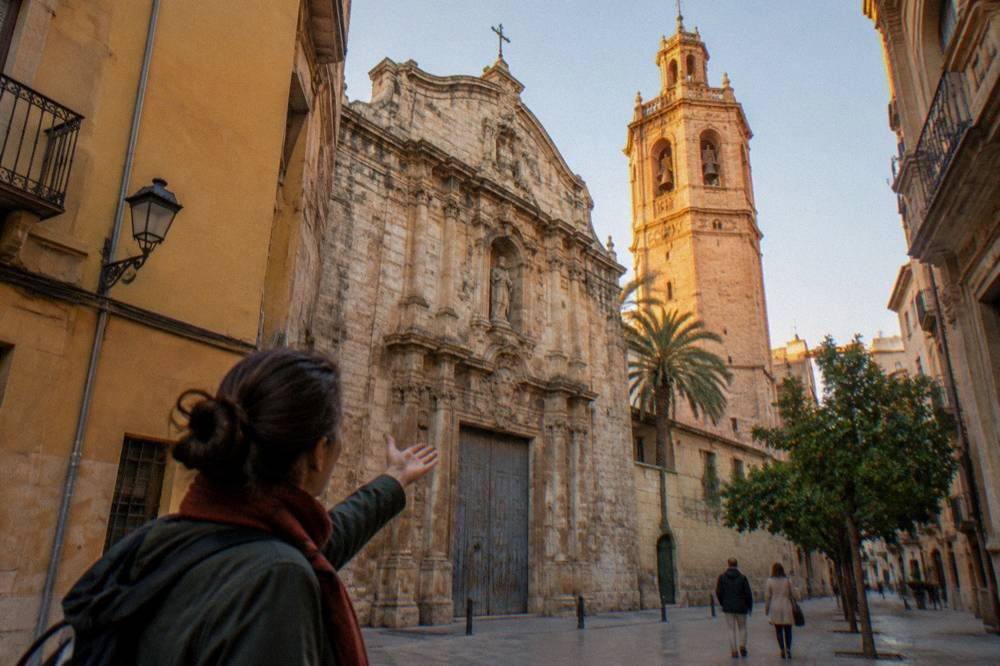A local guide gesturing toward the baroque facade of a church in Valencia's old town